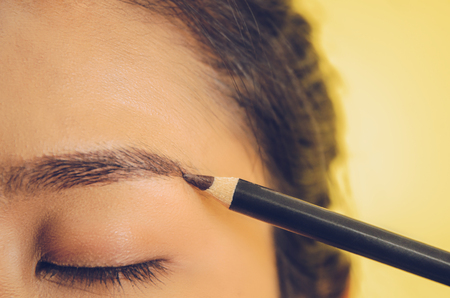 Beauty face of Asian woman by applying eyebrow pencil, The girl is makeup her face with eyebrow pencil, Soft and smooth face skin by cosmetics and foundation and using makeup brush on the face.の写真素材