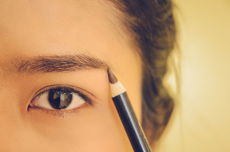 Beauty face of Asian woman by applying eyebrow pencil, The girl is makeup her face with eyebrow pencil, Soft and smooth face skin by cosmetics and foundation and using makeup brush on the face.の写真素材