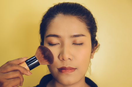 Beauty face of Asian woman by applying brushes, The girl is makeup her face with brush on, Soft and smooth face skin by cosmetics and foundation and using makeup brush on the face.の写真素材