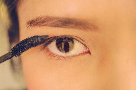 Beauty face of women by applying mascara on face, The girl is makeup her face with mascara, eyelash curler, Soft and smooth face skin by cosmetics, foundation and using makeup brush on the face.の写真素材