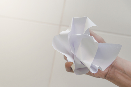 No idea and fail concept - Human hand holding crumpled paper or trash and white paper ball and waste on the floor, A hand are crumpling a paper, Recycling or fail creativity concept.の写真素材