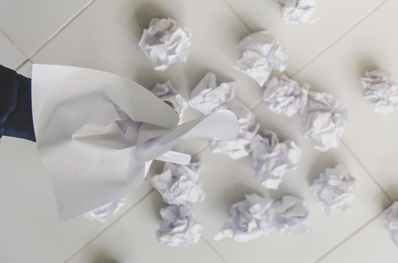 No idea and fail concept - Human hand holding crumpled paper or trash and white paper ball and waste on the floor, A hand are crumpling a paper, Recycling or fail creativity concept.の写真素材