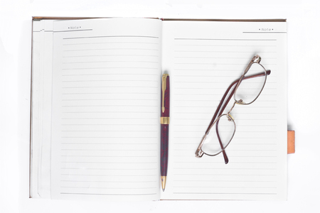 Glasses on notebook and pen on white background.の写真素材