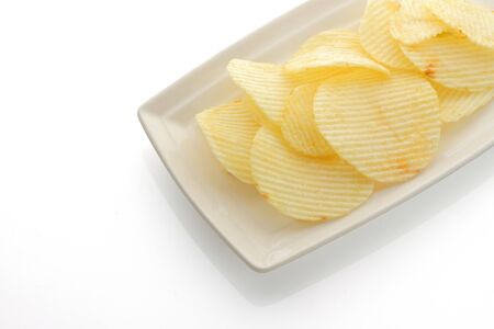 plate of ruffled potato chips isolated on a white backgroundの写真素材
