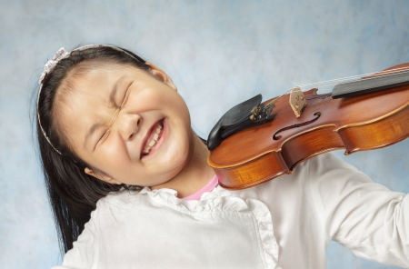 Cute little Asian girl playing the violin very enjoying .の写真素材