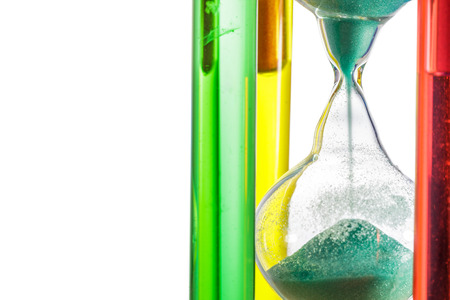 Colorful hourglass with green sand on white background.