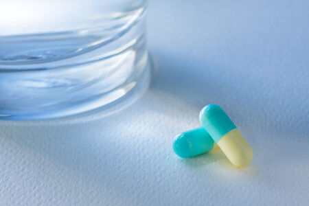 Glass of water and  pill on white background,with light blue.の写真素材