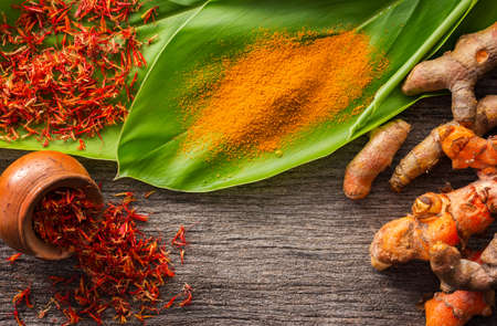 Turmeric and dry safflower on grunge wooden background.