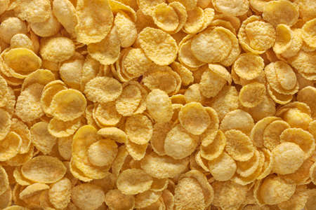 Corn flakes background. Cornflakes scattered on a table. Close up top view. cereal food for morning...