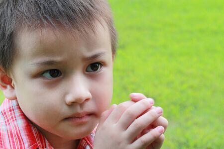 Boy face close-up on a background of green grass.の写真素材