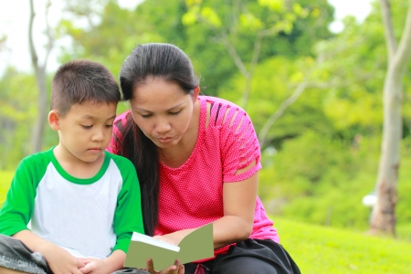 Mother and son reading a book, relaxing time in the gardenの写真素材