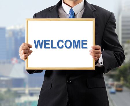 Businessman holding whiteboard with a message WELCOMEの写真素材