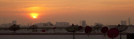 Satellite dish in the city at sunsetの写真素材