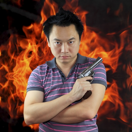Man holding gun with fire backgroundの写真素材