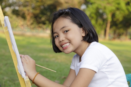 Asian little girl painting in the parkの写真素材
