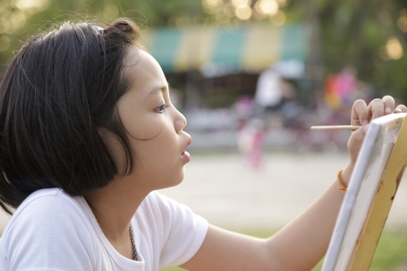 Asian little girl painting in the parkの写真素材