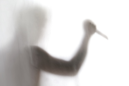 Shadow of men standing behind frosted glass and holding a knifeの写真素材