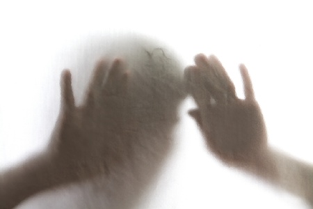 Shadow of men standing behind frosted glassの写真素材