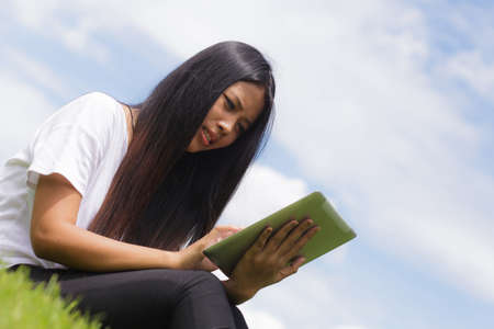 Asian woman using tablet computer in the parkの写真素材
