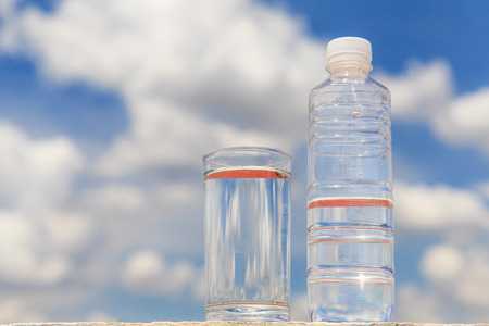 Glass of water and bottle on blue skyの写真素材