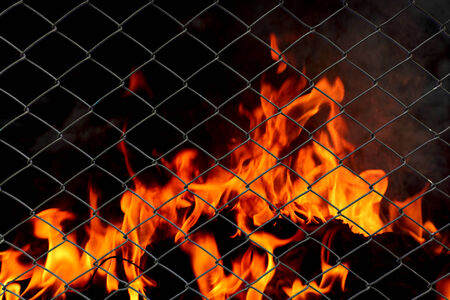 Metal net with flames burning backgroundの写真素材
