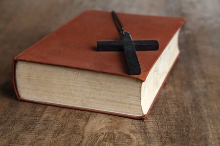 Cross over wood table with old book, holy Bibleの写真素材