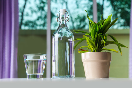 Glass of water with a bottle on table