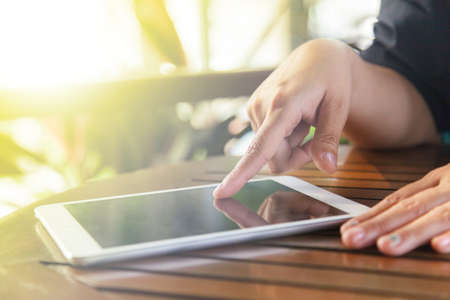 Cropped view of women using a digital tablet at outdoor coffee shop