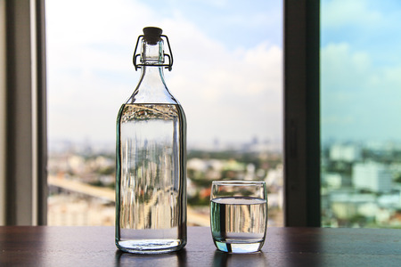Glass of water with a bottle on tableの写真素材