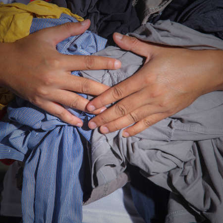 Hand holding a huge pile of clothesの写真素材