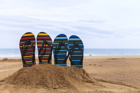Flip flops on the sandy beach with blue sea and skyの写真素材