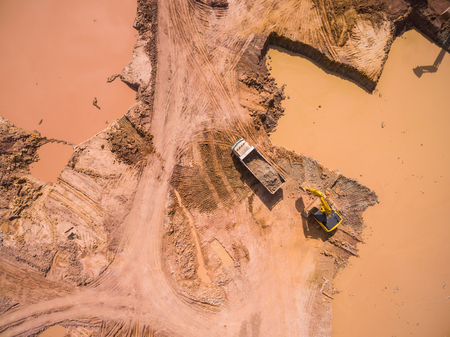 Aerial view of excavator and truck working on the fieldの写真素材