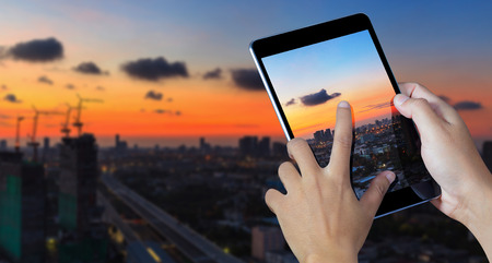 Hand holding the digital tablet with City backgroundの写真素材