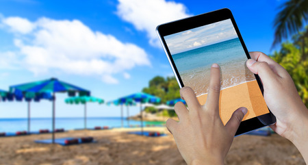 Hand holding the digital tablet with Sea and Beachesの写真素材