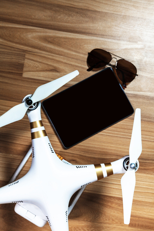 Top view of drone with sunglasses and tablets on wooden background, before the flight, Aerial shooting conceptの写真素材