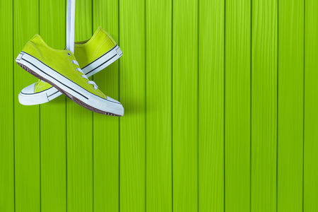 Pair of new green sneakers hanging on wooden wallの写真素材