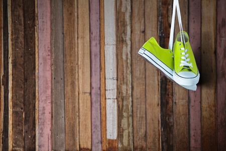 Pair of new green sneakers hanging on wooden wallの写真素材