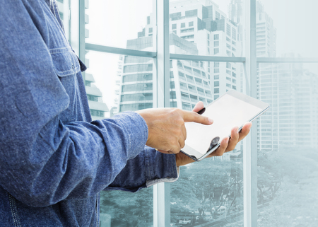 Businessman using digital tablet with modern buildingの写真素材