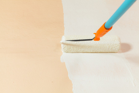 Painter painting the walls white in house