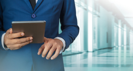 Businessman using digital tablet with modern building and social mediaの写真素材