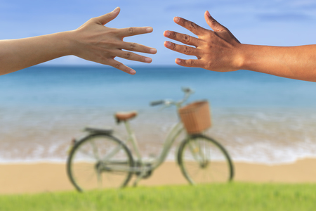 Two hands of man and woman at on sea side view with bicycle, Summer vacation conceptの写真素材