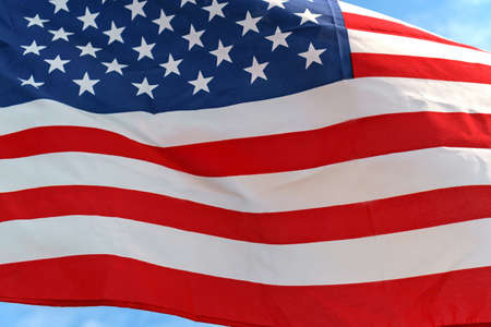 Waving star and stripes American flag on the blue sky