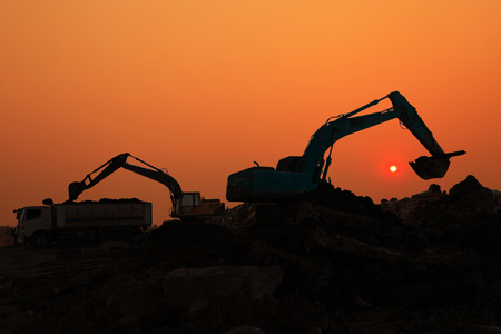 Silhouette of Excavator loader in construction site at sunset sky backgroundの写真素材