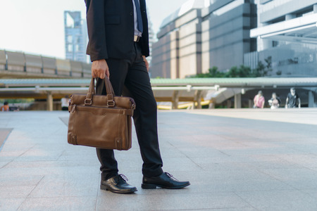 Businessman walking in the city and holding briefcaseの写真素材