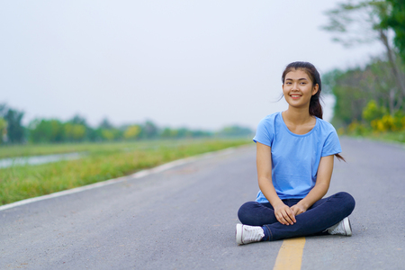 Woman sitting on the road in the parkの写真素材