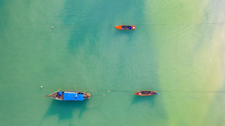 Aerial top view, Fishing boat, Tourist boat floating on a shallow clear sea, Beautiful bright blue water in the oceanの写真素材