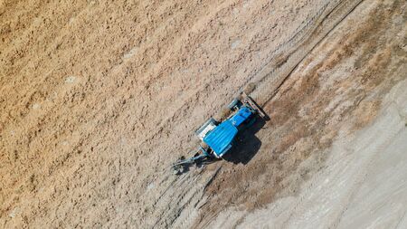 Top view of agricultural tractor vehicles working at fieldの写真素材