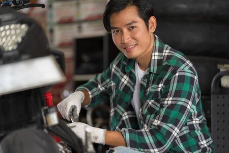 Cropped view of Mechanic using a wrench and socket on a motorcycle, Repairing and customized...