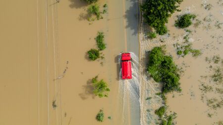 Aerial top view of Flooded the village and Country road with a red car, View from above shot by droneの写真素材
