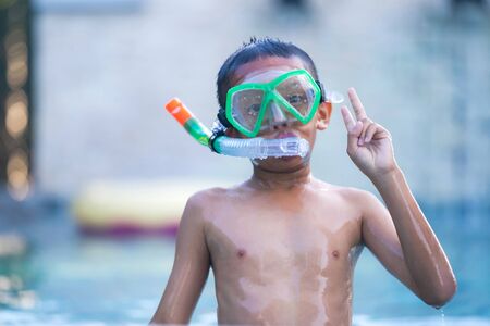 View of boy with swim glasses floating in the swimming poolの写真素材
